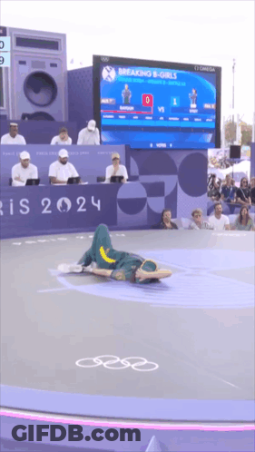 A Person Is Laying On The Floor In Front Of A Breaking B-Girls Sign GIF