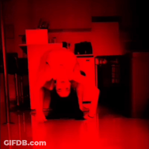 A Person Is Laying On Their Back In A Dark Room With A Red Light Behind Them GIF