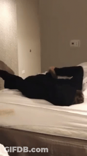 A Person Is Laying On Their Back On A Bed In A Bedroom GIF
