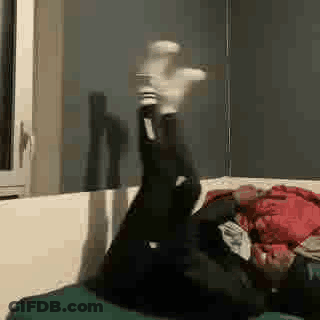 A Person Is Laying On Their Stomach On A Couch With Their Legs Up . GIF