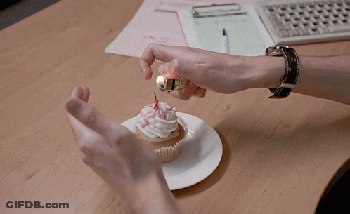 A Person Is Lighting A Cupcake With A Lighter GIF