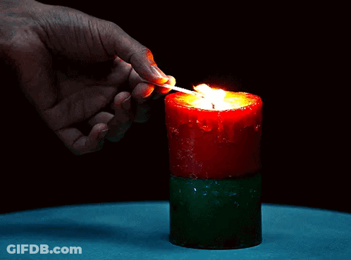 A Person Is Lighting A Red Candle With A Match GIF
