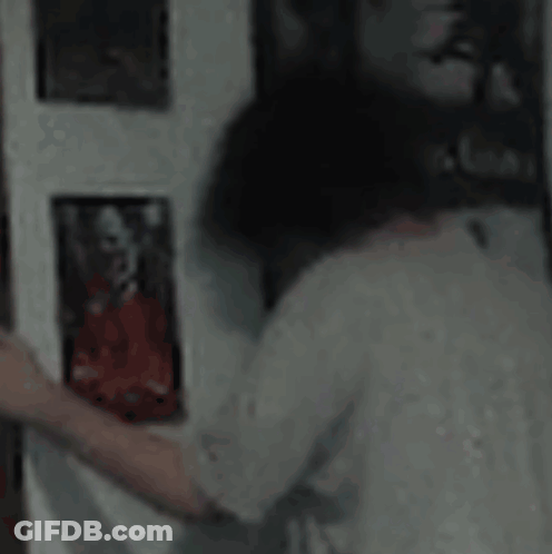 A Person Is Looking At A Picture On A Wall In A Room . GIF