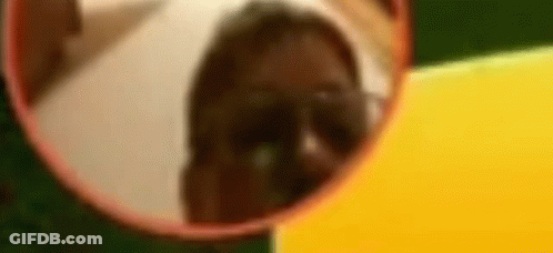 A Person Is Looking At Their Reflection In A Round Mirror . GIF
