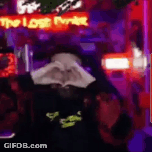 A Person Is Making A Heart Shape With Their Hands In Front Of A Neon Sign That Says `` The Lost Ever '' . GIF