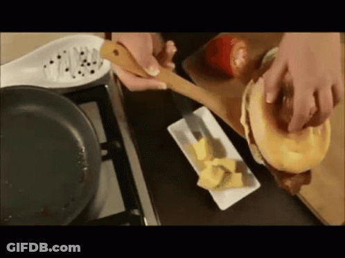 A Person Is Making A Sandwich With A Wooden Spoon GIF