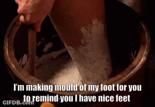 A Person Is Making Mould Of Their Foot In A Wooden Bucket . GIF