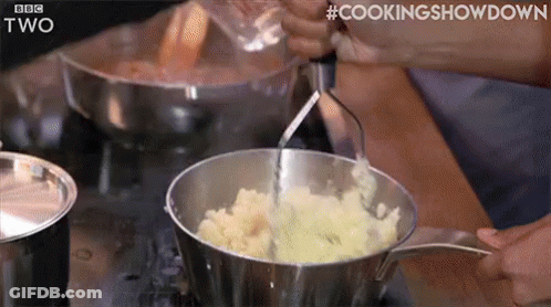 A Person Is Mashing Potatoes In A Pot . GIF