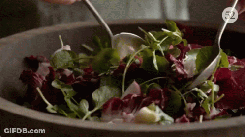 A Person Is Mixing A Salad In A Wooden Bowl With The Number 52 On The Bottom Right GIF