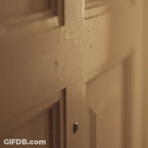 A Person Is Opening A Door With A Knife In Their Hand . GIF