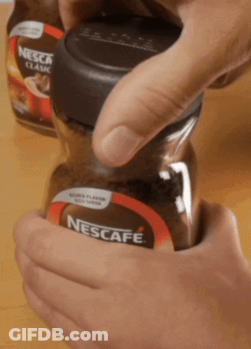 A Person Is Opening A Jar Of Nescafe Classic GIF