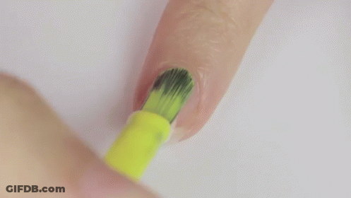 A Person Is Painting Their Nails With A Yellow Nail Polish Brush . GIF