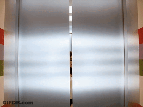 A Person Is Peeking Through A Sliding Glass Door In An Elevator GIF