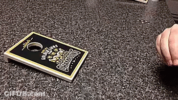 A Person Is Playing A Game Of Cornhole On A Counter Top GIF