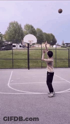 A Person Is Playing Basketball On A Court With A Basketball Hoop In The Background GIF