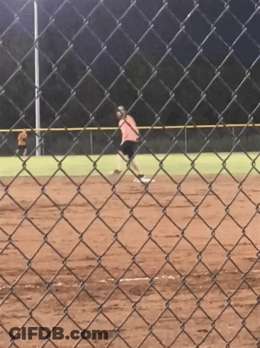 A Person Is Playing Softball On A Field Behind A Chain Link Fence GIF