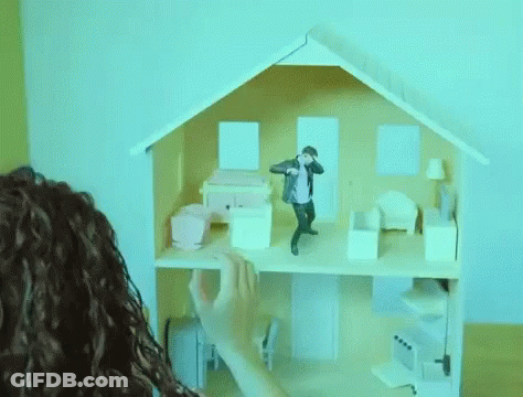 A Person Is Playing With A Doll House With A Man Standing On The Top Floor . GIF