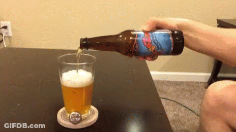 A Person Is Pouring A Bottle Of Beer Into A Glass On A Coaster GIF