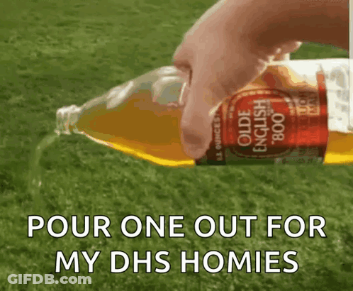 A Person Is Pouring A Bottle Of Olde English Apple Cider Into A Grassy Field . GIF