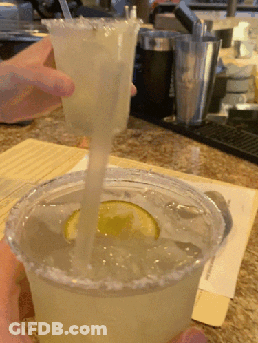 A Person Is Pouring A Drink Into A Plastic Cup With A Straw GIF