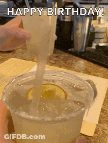 A Person Is Pouring A Drink Into A Plastic Cup With Ice And A Lime Slice . GIF