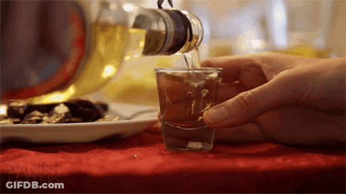 A Person Is Pouring A Shot Of Alcohol Into A Shot Glass GIF