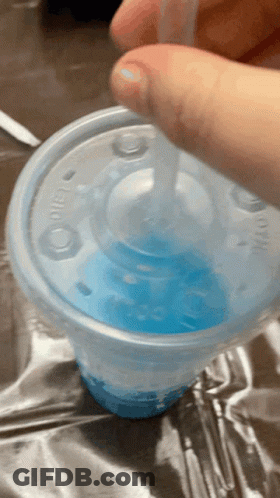 A Person Is Pouring Blue Liquid Into A Plastic Cup With A Straw GIF