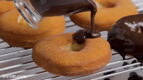 A Person Is Pouring Chocolate On A Donut On A Cooling Rack GIF