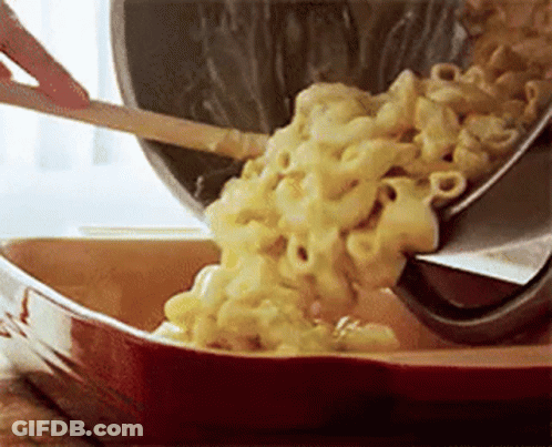 A Person Is Pouring Macaroni And Cheese Into A Casserole Dish With A Spatula . GIF