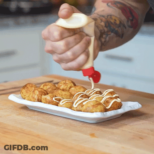 A Person Is Pouring Mayonnaise On A Plate Of Fried Food GIF