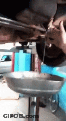 A Person Is Pouring Oil Into A Metal Tray Under A Car GIF