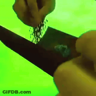 A Person Is Pouring Something Into A Black Object On A Green Screen GIF