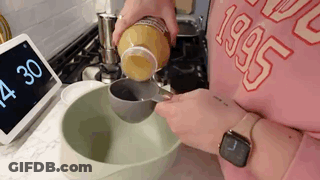 A Person Is Pouring Something Into A Bowl . GIF