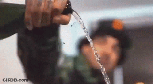 A Person Is Pouring Water From A Bottle Into Another Person 'S Face . GIF