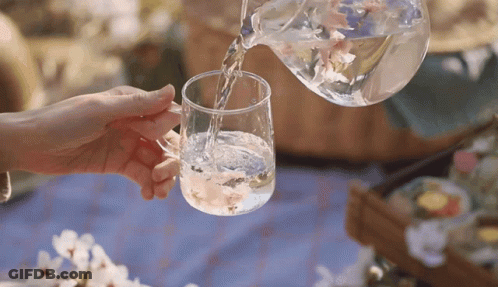 A Person Is Pouring Water Into A Glass Cup GIF