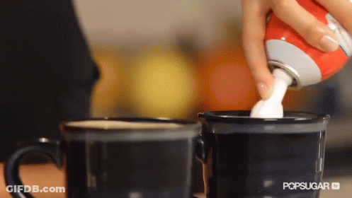 A Person Is Pouring Whipped Cream Into Two Coffee Cups GIF