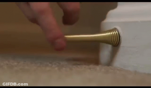 A Person Is Pressing A Door Stop On A Carpet . GIF