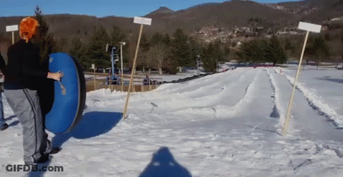 A Person Is Pushing A Blue Tube Down A Snow Covered Hill GIF