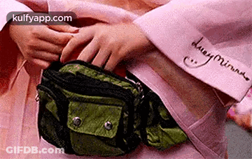 A Person Is Putting Something In A Green Fanny Pack . GIF