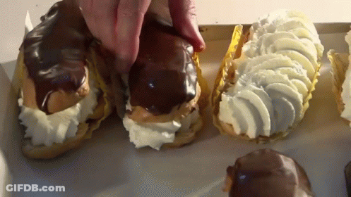 A Person Is Reaching For A Pastry With Whipped Cream GIF
