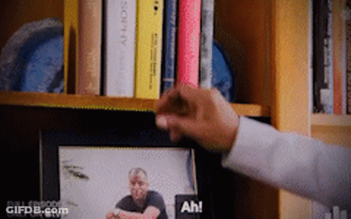 A Person Is Reaching For A Picture Of A Man On A Tv Screen GIF