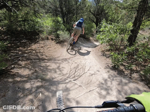 A Person Is Riding A Bike Down A Dirt Path GIF