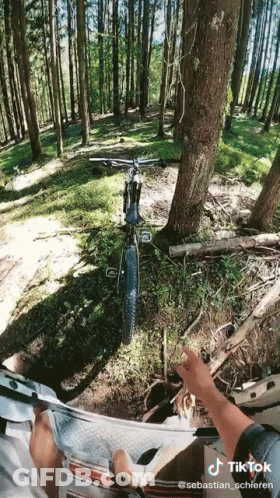 A Person Is Riding A Bike In The Woods With A Tiktok Watermark On The Bottom GIF