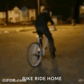 A Person Is Riding A Bike On A Street At Night . GIF