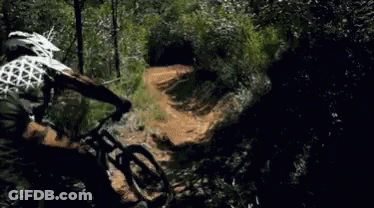 A Person Is Riding A Bike On A Trail In The Woods GIF