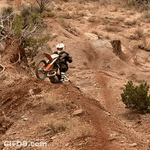 A Person Is Riding A Dirt Bike Down A Dirt Road GIF