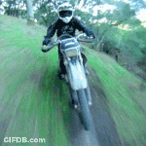A Person Is Riding A Dirt Bike On A Grassy Hill GIF
