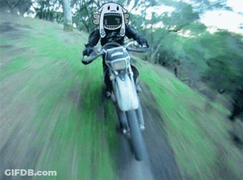 A Person Is Riding A Dirt Bike With A Cartoon Character On Their Face GIF