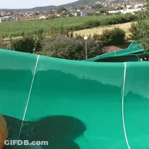 A Person Is Riding A Green Water Slide In A Park GIF
