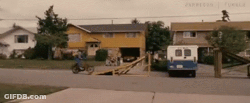 A Person Is Riding A Motorcycle Down A Ramp In Front Of A House . GIF